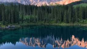 Drone view of Karersee lake Dolomites, Italy, lake Carezza in the Italian Alps, peaceful scenic view of alpine lake at dawn with mirror reflection of mountain peaks in water - Powered by Shutterstock - Get 15% off with code: PIKWIZARD15