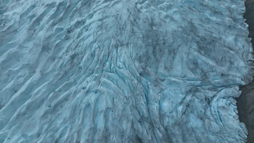 A close-up reveals deep crevasses and blue textures on the surface of the Svartisen glacier, Norway