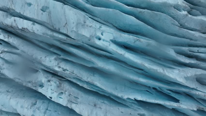 A close-up glacial footage capturing the fine textures, crevices, and shimmering blue tones of Engabreen ancient ice in motionless stillness