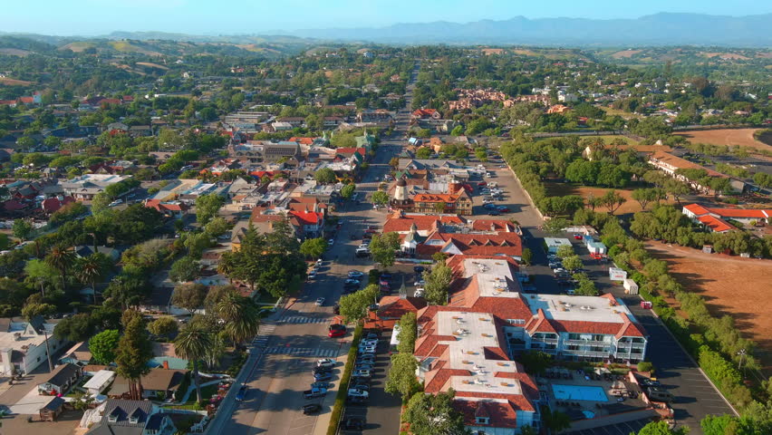 Smooth aerial zoom in revealing the charming architecture and urban layout of Solvang, a Danish-inspired town in Southern California during spring.