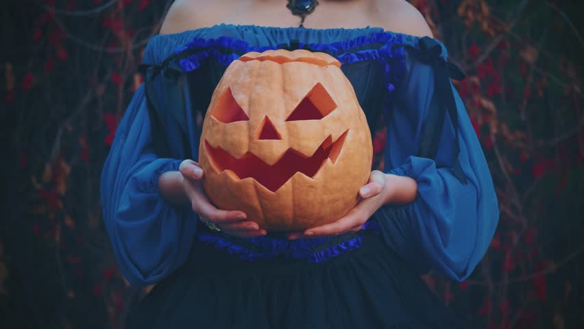 unrecognizable person Close-up portrait Halloween orange pumpkin lantern. Witch female hands hold jack o lantern. Girl cropped face body part. Silhouette Medieval style woman Carnival creative costume