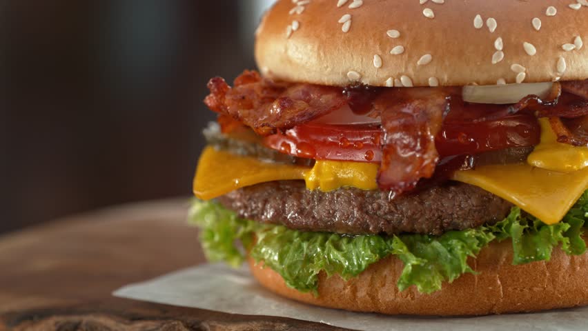 Tasty home made burger with camera movement and rotating . Delicious burger with fresh cabbage, cheese, onions, bacon, tomatoes and grilled beef steak.
