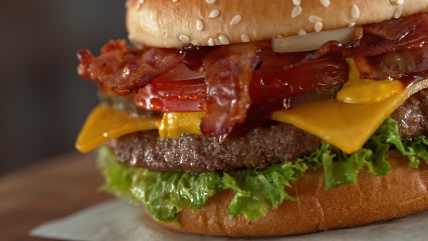 Tasty home made burger with camera movement and rotating . Delicious burger with fresh cabbage, cheese, onions, bacon, tomatoes and grilled beef steak.