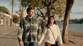 A young couple holds hands and walks along the Guadalquivir River in Seville, Spain, on a sunny day. They are happy and in love. - Powered by Shutterstock - Get 15% off with code: PIKWIZARD15
