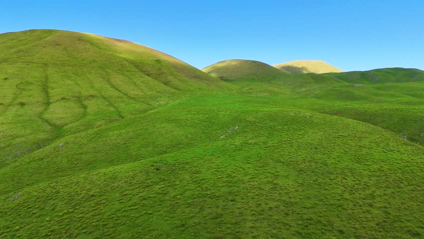 Aerial view of green hills under blue sky, United States.