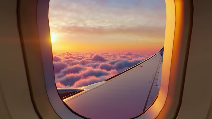 Airplane Window View Above the Clouds at Sunset. Beautiful purple and orange sky. Aerial view of Cloudscape. Airplane wing in sky. View through porthole from passenger seat