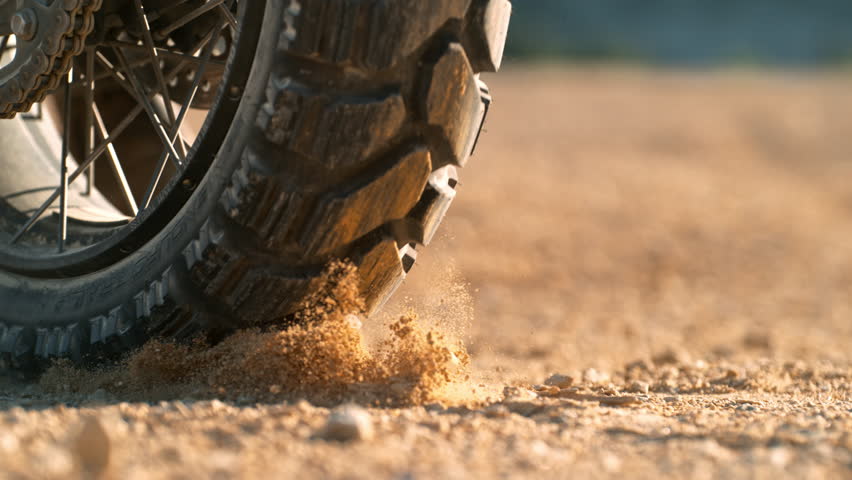 Super slow motion of flying rocks and dust from the wheel of a motocross bike at the start of the race