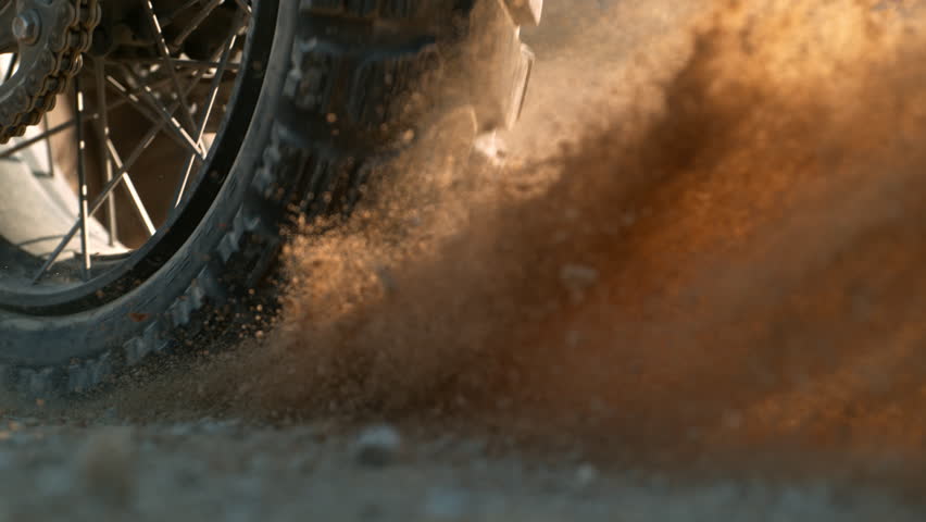 Super slow motion of flying rocks and dust from the wheel of a motocross bike at the start of the race