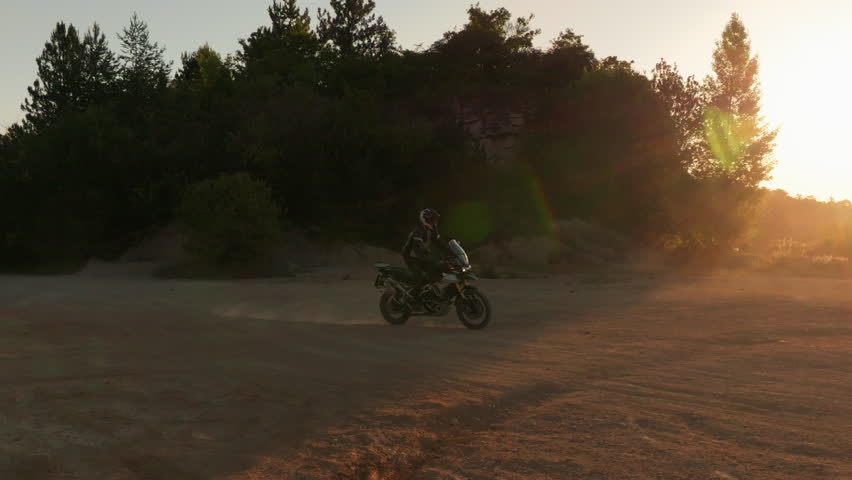 Slow motion shot of a rider on a motorcycle riding in dusty terrain