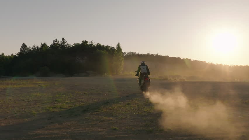 Slow motion shot of a rider on a motorcycle riding in dusty terrain