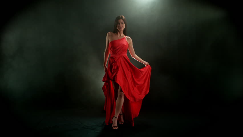 Brunette Woman in Ruby Red Dress Posing Against a Black Background . Filmed on High Speed Cinematic Camera in Super Slow Motion