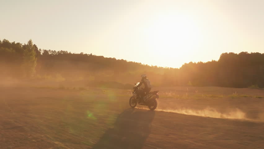 Slow motion shot of a rider on a motorcycle riding in dusty terrain