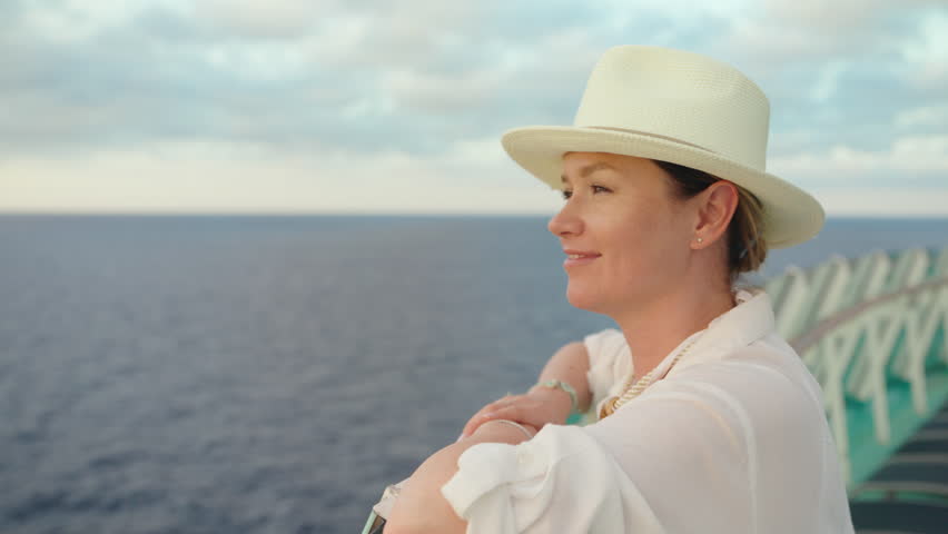 A stylish woman in a chic white outfit and fashionable hat enjoys the stunning ocean view on a luxurious cruise ship, embodying relaxation and tranquility during her delightful journey