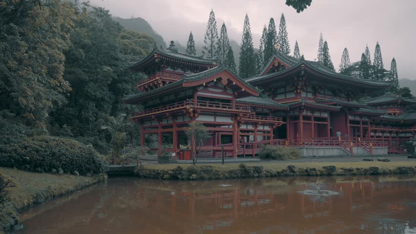 view of  religious Japanese style architecture building with tree on foreground. The Byodo-In Temple during cloudy rainy day