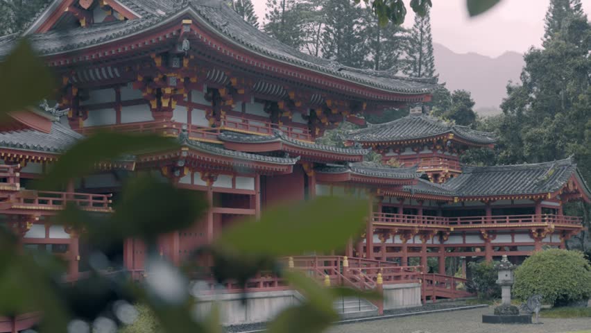 view of  religious Japanese style architecture building with tree on foreground. The Byodo-In Temple during cloudy rainy day