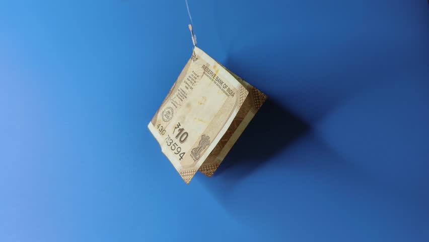 Indian rupee money or currency note hooked on fishing hook like lure or bait Isolated against a blue background with copy space. debt, scam, rat race, phishing, financial trap and inflation concept.