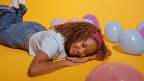 Young african american woman enjoying, dancing and relaxing on a yellow background with colorful balloons, slow motion - Powered by Shutterstock - Get 15% off with code: PIKWIZARD15