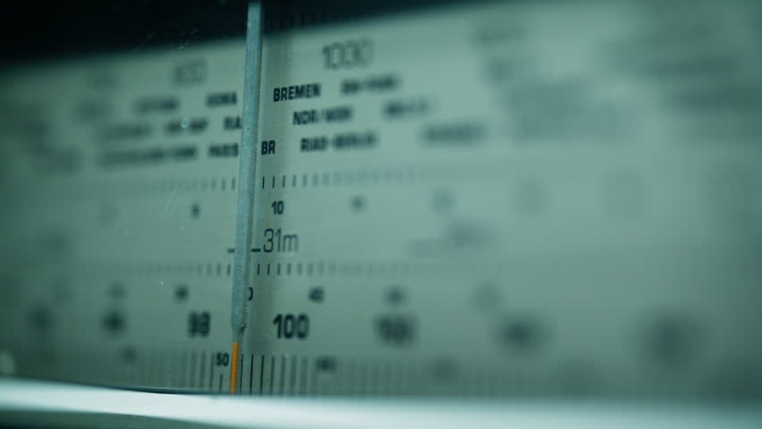 Detailed shot of antique radio dial showing signal numbers and tuning label. Soft glow creating retro feeling in quiet room. Classic device reflecting past sound systems and manual broadcast control