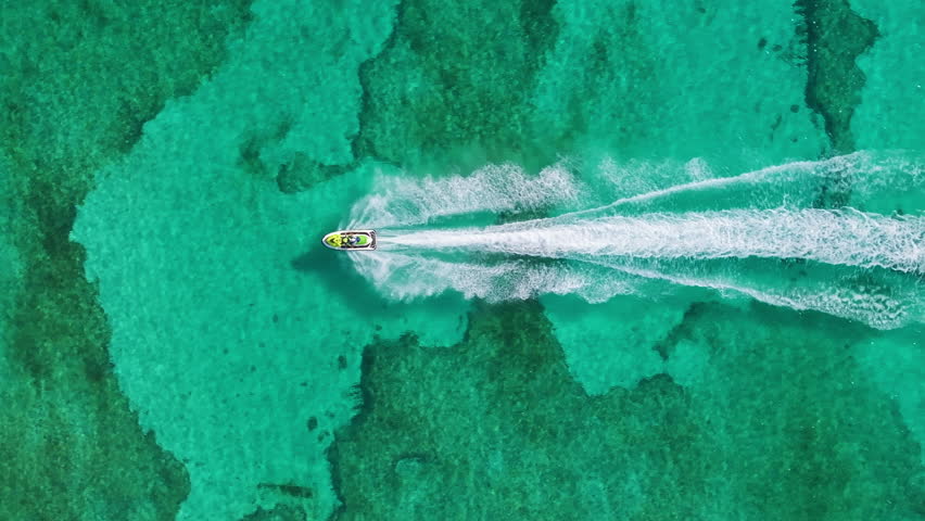 Aerial footage captures a jet ski gliding over Cozumels clear turquoise waters, showcasing the vibrant marine life beneath, inviting viewers to explore this tropical paradise and its natural beauty