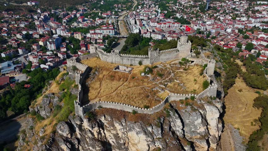 Boyabat Castle Sinop aerial drone view of  on a rocky cliff, Turkey. The ancient fortress overlooks the town, with visible stone walls and a dramatic drop, under bright and clear sky conditions 4k 