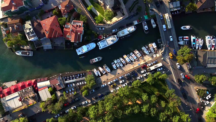 Top-down drone view of Anadolu Fortress in Istanbul’s Asian side, surrounded by yachts, coastal homes, narrow streets, and lush greenery along the scenic Bosphorus shoreline. 4k ultrahd Turkiye