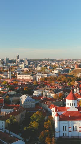 Beautiful vertical aerial Vilnius city Old town panorama in autumn with orange and yellow foliage. Aerial sunny evening view. Cathedral of the Theotokos. Fall city scenery in Vilnius, Lithuania