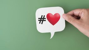 animated video of hand holding  white speech bubble with hashtag sign and couple red hearts on green background, health care,  valentine concept - Powered by Shutterstock - Get 15% off with code: PIKWIZARD15