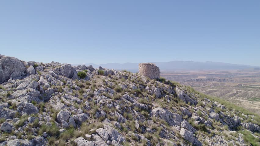 Ruins of a medieval watchtower on a rocky mountaintop. Aerial view of the watchtower and horizon. Spain.