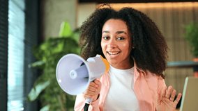 Excited African American woman holding a megaphone and speaking enthusiastically in a modern office setting. Girl appears happy and confident, making an important announcement or sharing news. - Powered by Shutterstock - Get 15% off with code: PIKWIZARD15