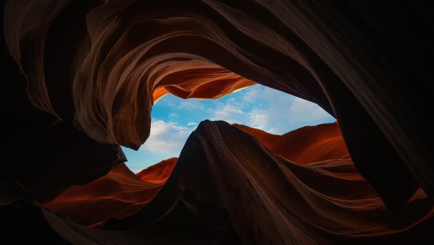 Time lapse of blue sky and moving clouds framed by Lower Antelope Canyon sandstone rock walls, Arizona
