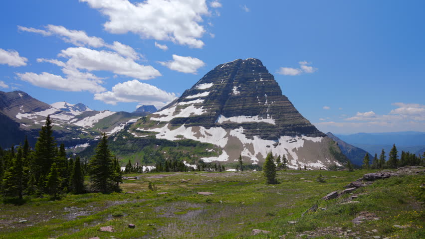 Explore the breathtaking landscapes of Glacier National Park in Montana, featuring impressive mountains, vibrant greenery, and stunning blue skies that will leave you in awe on your outdoor adventure