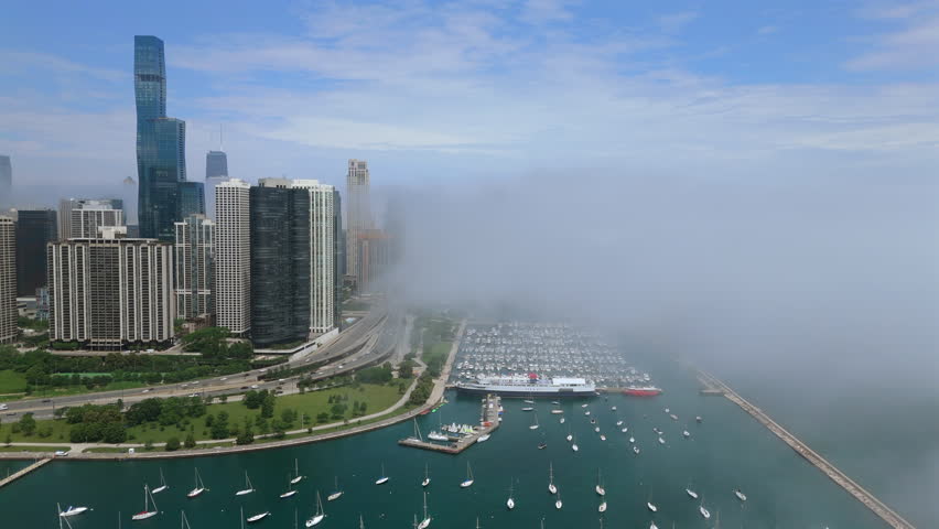 Chicago 06.20.2025. Stunning and breathtaking aerial view of Chicago vibrant modern skyline covered in fog, showcasing its iconic architecture, along with a beautiful harbor filled with various boats