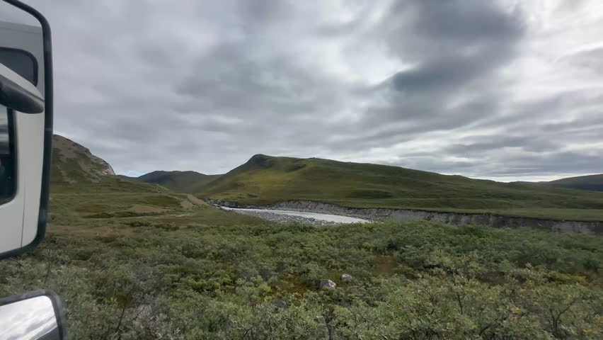 A panoramic view from a vehicle in Kangerlussuaq, Greenland, highlighting the lush green landscape and cloudy skies, tc01
