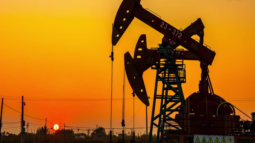 Silhouetted against colorful sunset sky with Industrial oil drilling derrick at desert oilfield. oil rigs pump energy machine for petroleum in desert on the blue sky background. Gas onshore production