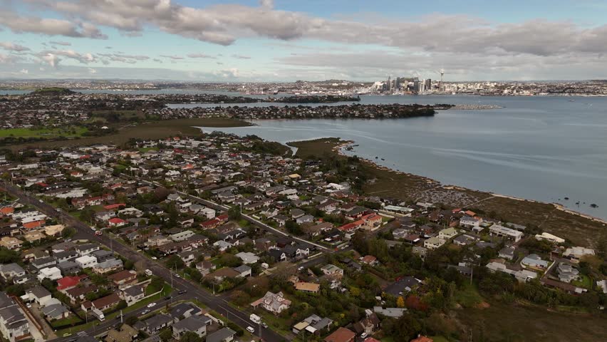 Takapuna, coastal suburb with residential homes, Auckland CBD, skyline and Sky Tower, Waitemata Harbour. New Zealand