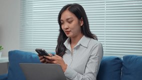 Young business professional efficiently multitasking, engaging with smartphone and laptop, expressing positive emotions while working remotely from a cozy home environment - Powered by Shutterstock - Get 15% off with code: PIKWIZARD15