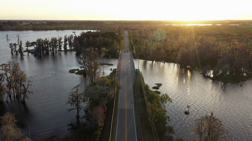 Car Driving Through Palatlakaha Minnehaha Bridge Over Lake Minnehaha At Sunset In Clermont, Florida, USA. - aerial shot