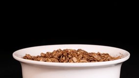 Granola grains cascade into a white bowl, set against a black background, highlighting texture and motion in a 15-second sequence - Powered by Shutterstock - Get 15% off with code: PIKWIZARD15