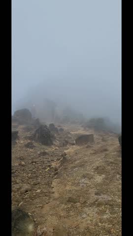 Misty Mountain Pathway with Rocks and Travelers in Dense Foggy Conditions