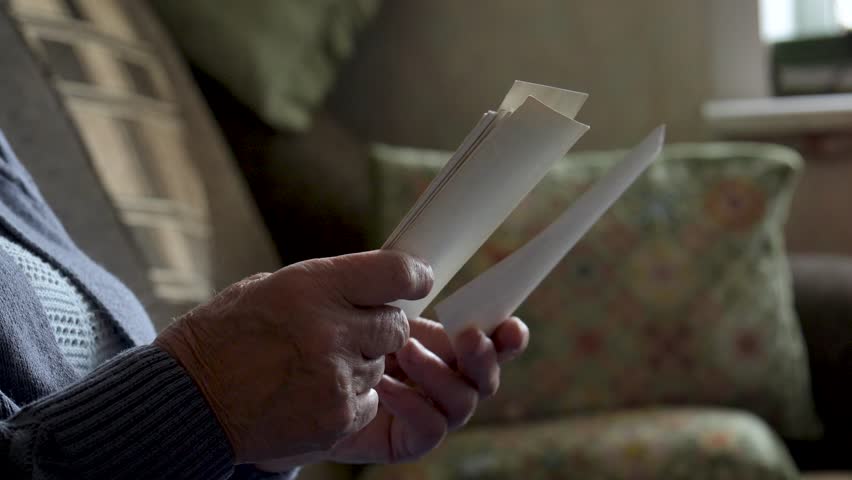 Close up wrinkled hands gently hold stack of vintage photographs. Turning each photo with nostalgic touch, evoking cherished memories bygone days. Unrecognizable person. Nursing home life. Old people