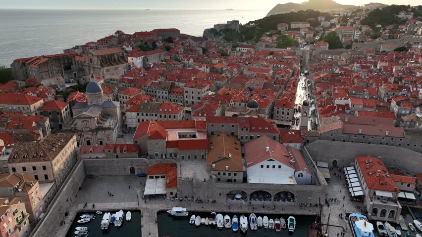 Dubrovnik Old Town in Croatia, pan over historic red roofs and harbor, aerial shot