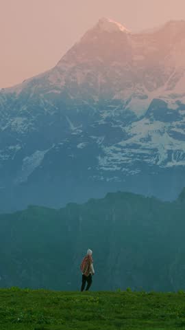 An excited, joyful man celebrates his win after receiving great news, smiling with pure happiness. People are celebrating around him, surrounded by beautiful mountain scenery in the summer.