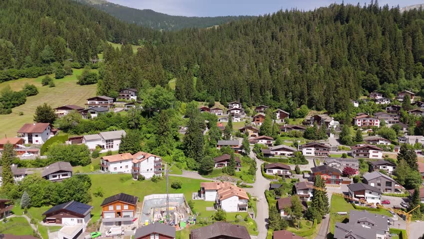 Two-story houses and homes in Swiss style located on hillside of alps. Sunny day in summer. aerial view. Holidays in Switzerland theme.