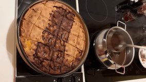 A woman's hand with a ladle is soaking a homemade baked cake. A sweet syrup of water, sugar, butter, and cocoa is boiled in a pot. Making a pastry at home. Comfort food. Cake soak. - Powered by Shutterstock - Get 15% off with code: PIKWIZARD15
