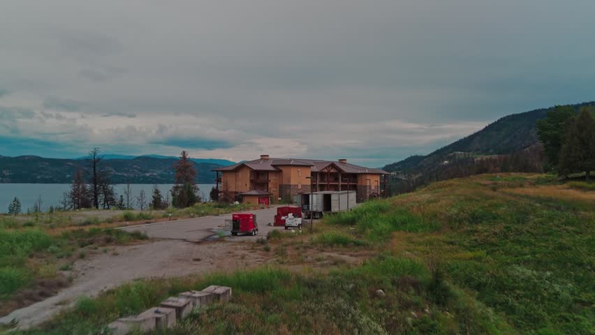Drone fast approaching flyover deserted parking lot abandoned resort Majestic Okanagan Lake behind then over hotel building revealing park boat dock launch marina vast waters