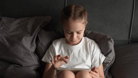 child playing tablet, little girl playing tablet, Girl on bed, looking happy, holding a tablet, playing a game, wearing white pajamas, evening time, cozy atmosphere, indoor lighting, relaxing moment - Powered by Shutterstock - Get 15% off with code: PIKWIZARD15