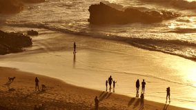 Lisbon, Portugal: Golden sunset casting a warm glow over the beach, with tourists walking along the shore, playing in the sand, and savoring the stunning scenery. Summer travel vacation background - Powered by Shutterstock - Get 15% off with code: PIKWIZARD15