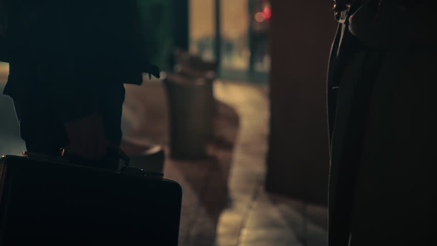 Briefcase exchange between two people in low light. Suspenseful, covert transaction perfect for spy thriller, crime drama, espionage, secret deal, or noir-style footage. undercover agents work.