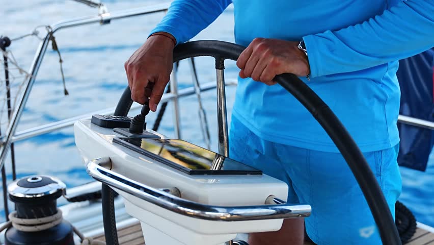 Man steering a sailing yacht using navigation display and control panel near Croatia. Precision, control and modern sailing lifestyle at sea. High quality 4k footage
