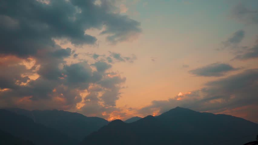 Landscape shot of sunset with clouds above the Himalayan mountains during the monsoon season as seen from Naggar near Manali in Himachal Pradesh, India. Clouds above the Himalayas in sunset.